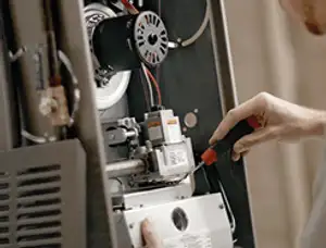 Furnace repair technician inspecting internal components and wiring in Lafayette, LA