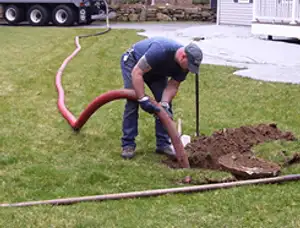 Septic pumping technician servicing a residential septic tank with a vacuum hose in Lafayette, LA