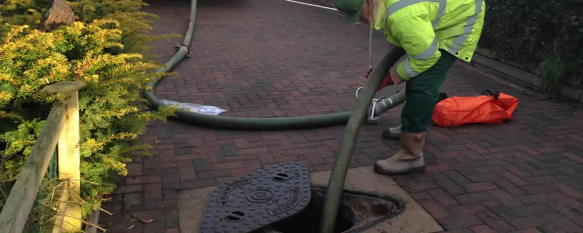 Septic tank cleaning technician servicing a septic tank with a vacuum hose in Lafayette, LA